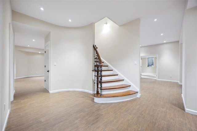staircase with wood finished floors, baseboards, and recessed lighting