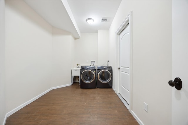 laundry room featuring separate washer and dryer, dark wood finished floors, and baseboards
