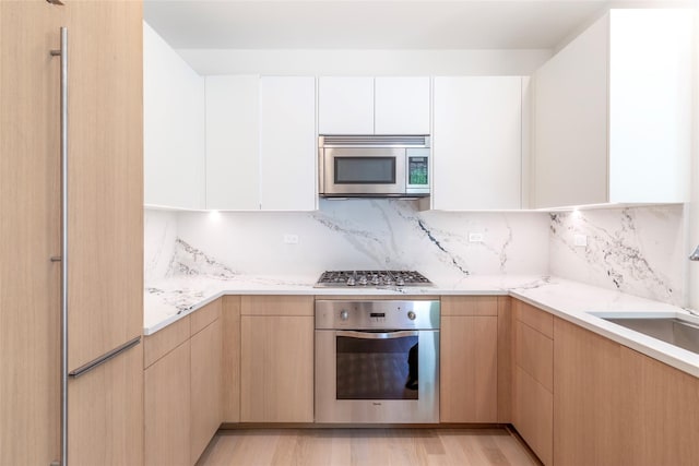 250 E 49th St Unit 5F, New York Manhattan, NY 10017 - kitchen with stainless steel appliances, a sink, backsplash, white cabinetry, and modern cabinets