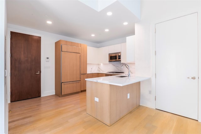250 E 49th St Unit 5F, New York Manhattan, NY 10017 - kitchen featuring built in fridge, stainless steel microwave, a peninsula, light wood finished floors, and light countertops