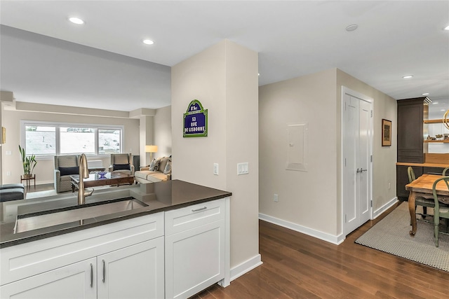 433 Main St Unit 203, Port Washington, NY 11050 - kitchen with a sink, dark countertops, dark wood finished floors, baseboards, and white cabinetry