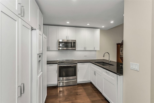 433 Main St Unit 203, Port Washington, NY 11050 - kitchen featuring stainless steel appliances, a sink, dark countertops, dark wood-type flooring, and white cabinetry