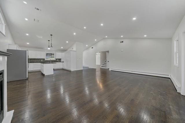 65 Old Cahoonzie Rd, Sparrowbush, NY 12780 - unfurnished living room with vaulted ceiling, baseboard heating, a fireplace, dark wood-style flooring, and recessed lighting