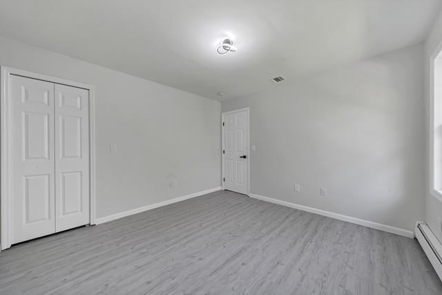 65 Old Cahoonzie Rd, Sparrowbush, NY 12780 - unfurnished bedroom with baseboard heating, wood finished floors, baseboards, and a closet