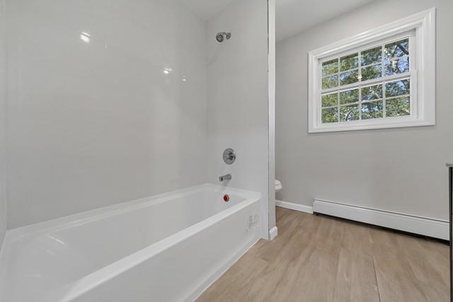 65 Old Cahoonzie Rd, Sparrowbush, NY 12780 - full bath with a baseboard radiator, toilet, wood finished floors, baseboards, and shower / bathtub combination