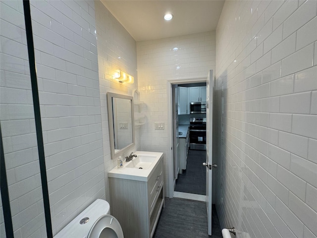 579 Van Siclen Ave, Brooklyn, NY 11207 - bathroom featuring tile walls, vanity, toilet, wood finished floors, and recessed lighting