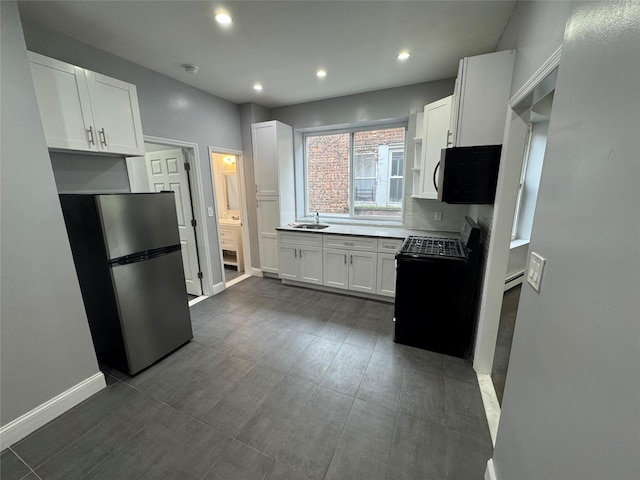 579 Van Siclen Ave, Brooklyn, NY 11207 - kitchen with freestanding refrigerator, gas stove, a sink, white cabinetry, and baseboards