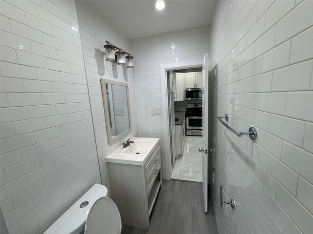 579 Van Siclen Ave, Brooklyn, NY 11207 - bathroom featuring tile walls, toilet, vanity, and tile patterned flooring