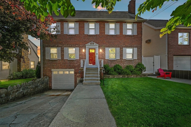 269 Hayward St, Yonkers, NY 10704 - view of front of house featuring concrete driveway, an attached garage, a chimney, brick siding, and a front lawn