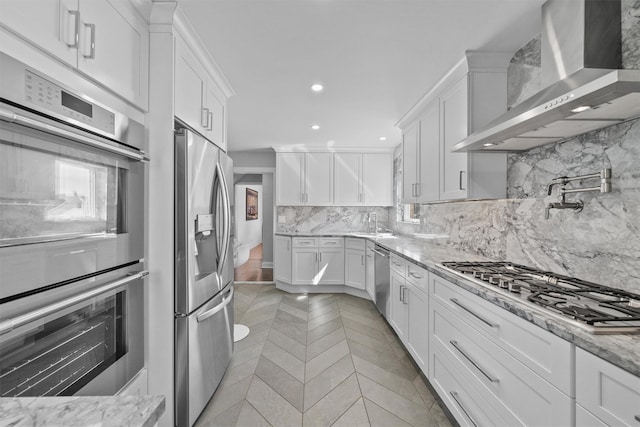 269 Hayward St, Yonkers, NY 10704 - kitchen with wall chimney exhaust hood, appliances with stainless steel finishes, white cabinetry, decorative backsplash, and recessed lighting