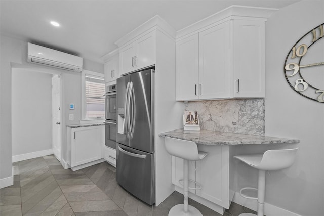 269 Hayward St, Yonkers, NY 10704 - kitchen featuring appliances with stainless steel finishes, a wall mounted air conditioner, white cabinetry, backsplash, and light stone counters