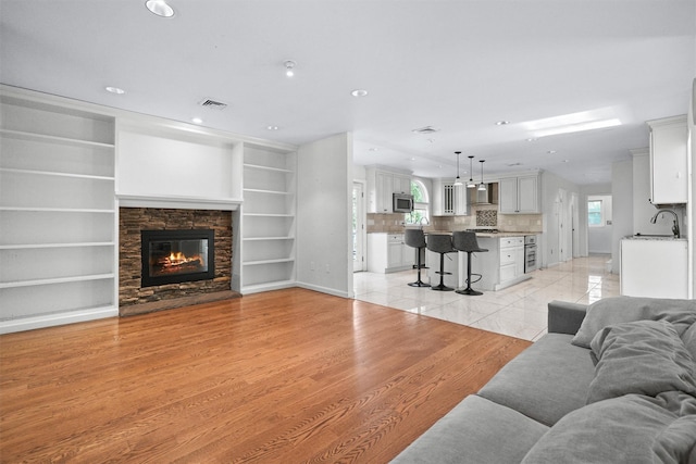 32 Wilder Rd, Monsey, NY 10952 - living room with a fireplace, recessed lighting, built in shelves, and light wood-style flooring