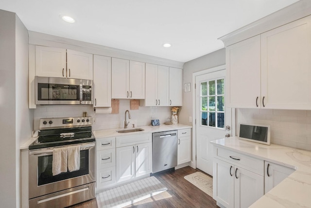 kitchen with appliances with stainless steel finishes, a sink, backsplash, white cabinets, and recessed lighting