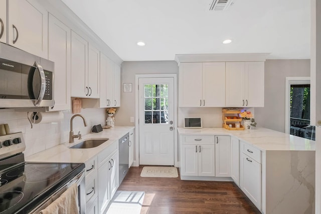 kitchen with stainless steel appliances, a sink, a peninsula, tasteful backsplash, and recessed lighting