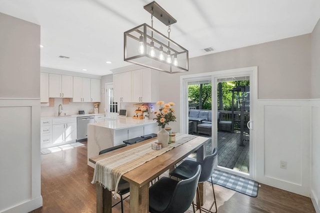 dining room featuring a wainscoted wall, dark wood finished floors, and a decorative wall