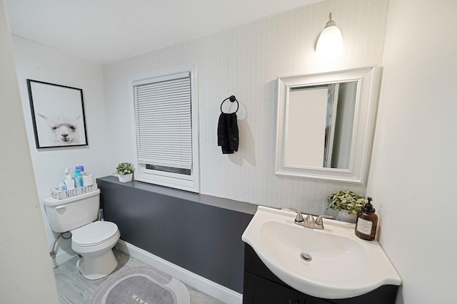 bathroom featuring toilet, vanity, and baseboards