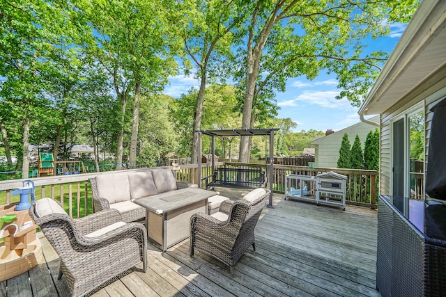 wooden deck with an outdoor living space, a playground, and view of wooded area