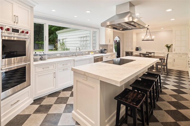 50 Kerry Ln, Chappaqua, NY 10514 - kitchen with appliances with stainless steel finishes, island exhaust hood, dark flooring, arched walkways, and a kitchen breakfast bar