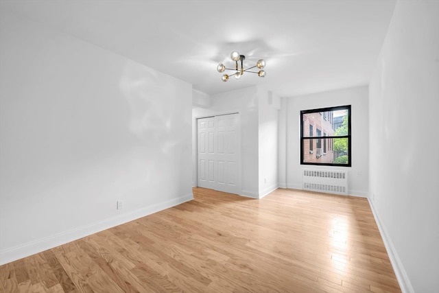 99-52 66th Rd Unit 3G, Rego Park, NY 11374 - spare room with radiator heating unit, a chandelier, and light wood-type flooring