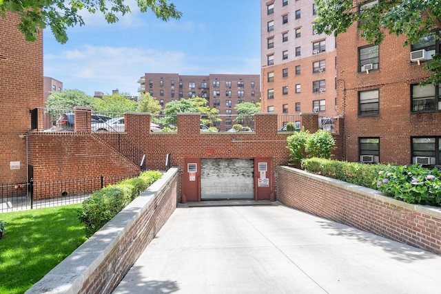 99-52 66th Rd Unit 3G, Rego Park, NY 11374 - view of property featuring concrete driveway, a garage, and cooling unit