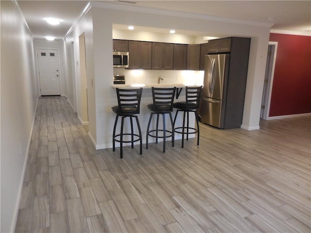 350 N Water St Unit 1-7, Newburgh, NY 12550 - kitchen with stainless steel appliances, a breakfast bar, ornamental molding, light countertops, and light wood-style flooring
