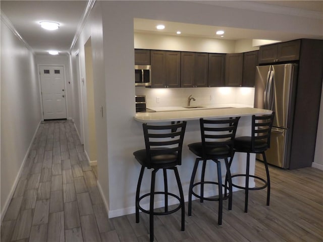 350 N Water St Unit 1-7, Newburgh, NY 12550 - kitchen featuring stainless steel appliances, wood finished floors, crown molding, dark brown cabinetry, and baseboards