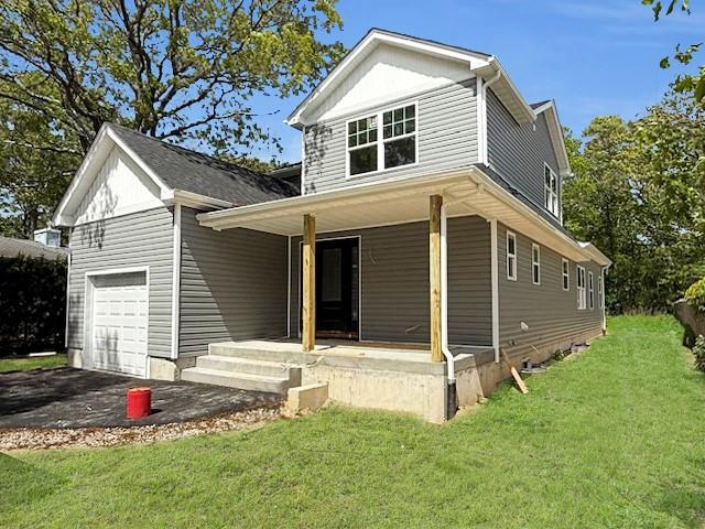 114 W End Dr, Shirley, NY 11967 - view of front of house with a porch, a garage, a front lawn, and driveway