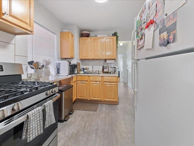 429 Revere Ave, Bronx, NY 10465 - kitchen with freestanding refrigerator, stainless steel gas range, decorative backsplash, and light brown cabinets