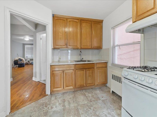 429 Revere Ave, Bronx, NY 10465 - kitchen featuring white gas range, radiator heating unit, a sink, under cabinet range hood, and light countertops