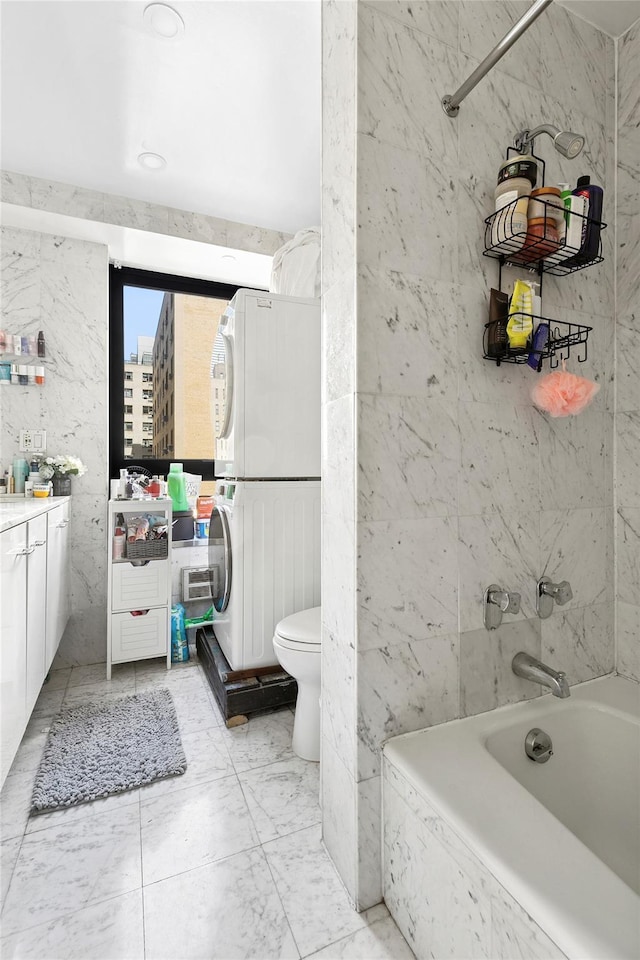 415 E 54th St Unit 10E, New York Manhattan, NY 10022 - full bathroom featuring estacked washer and dryer, vanity, a tub, toilet, and marble finish flooring
