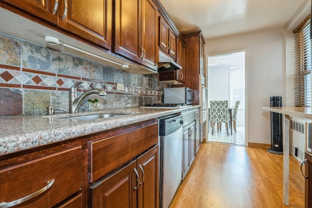 18-50 211th St Unit 2D, Bayside, NY 11360 - kitchen with stainless steel appliances, a sink, under cabinet range hood, light wood-type flooring, and light stone countertops