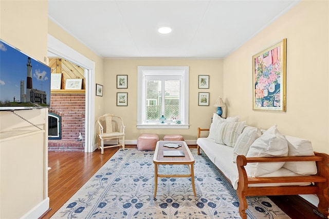 910 New Suffolk Ave, Mattituck, NY 11952 - living room with wood finished floors, baseboards, a fireplace, and crown molding