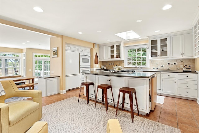 910 New Suffolk Ave, Mattituck, NY 11952 - kitchen featuring fridge, dark countertops, a skylight, a breakfast bar, and recessed lighting