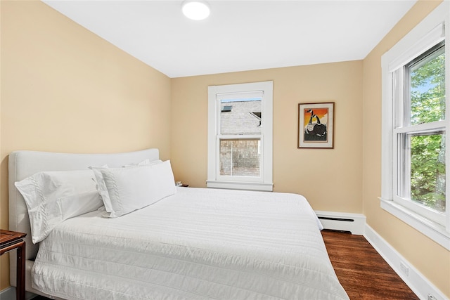 910 New Suffolk Ave, Mattituck, NY 11952 - bedroom featuring multiple windows, dark wood-type flooring, a baseboard radiator, and baseboards