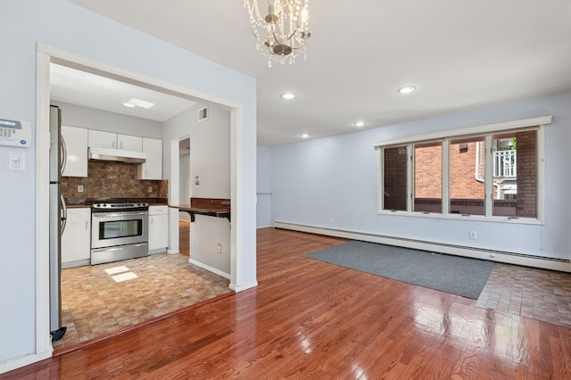 200-15 16th Ave, Bayside, NY 11360 - kitchen featuring appliances with stainless steel finishes, under cabinet range hood, dark countertops, baseboard heating, and white cabinetry