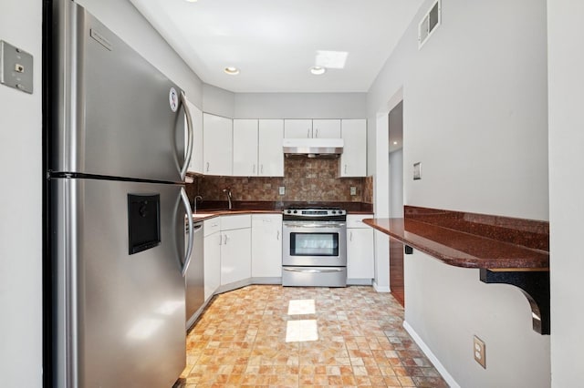 200-15 16th Ave, Bayside, NY 11360 - kitchen featuring stainless steel appliances, under cabinet range hood, dark countertops, tasteful backsplash, and white cabinets