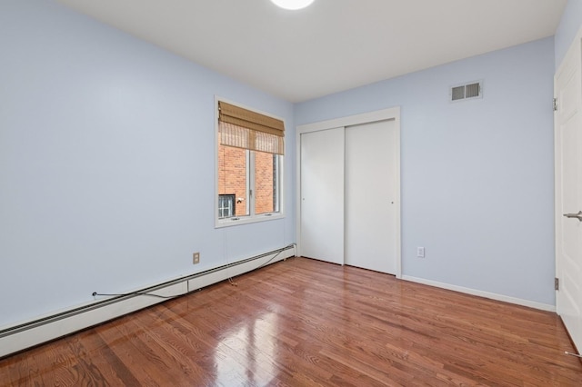 200-15 16th Ave, Bayside, NY 11360 - unfurnished bedroom featuring a baseboard radiator, wood finished floors, a closet, and baseboards
