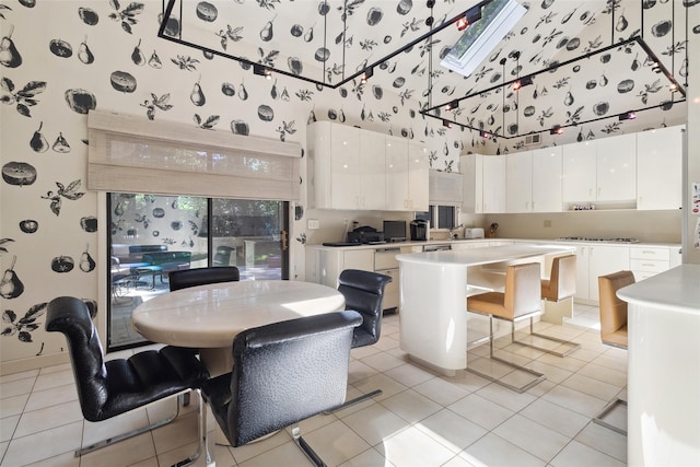 1 Polly Pk Rd, Rye, NY 10580 - kitchen featuring wallpapered walls, a high ceiling, white cabinets, a kitchen island, and light tile patterned floors