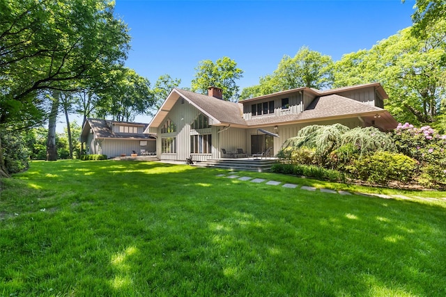 1 Polly Pk Rd, Rye, NY 10580 - back of property with a chimney, a lawn, board and batten siding, a wooden deck, and roof with shingles