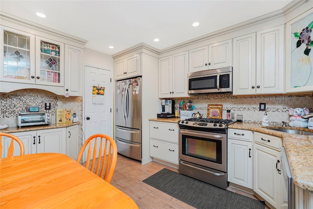 35 Futurity Pl, Staten Island, NY 10312 - kitchen featuring appliances with stainless steel finishes, backsplash, a sink, glass insert cabinets, and light wood-style floors