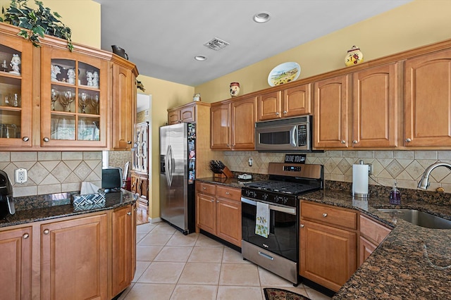 5 Mantack Path, Kings Park, NY 11754 - kitchen featuring appliances with stainless steel finishes, a sink, light tile patterned floors, dark stone countertops, and glass insert cabinets