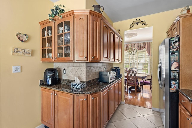 5 Mantack Path, Kings Park, NY 11754 - kitchen featuring freestanding refrigerator, light tile patterned floors, glass insert cabinets, backsplash, and dark stone counters
