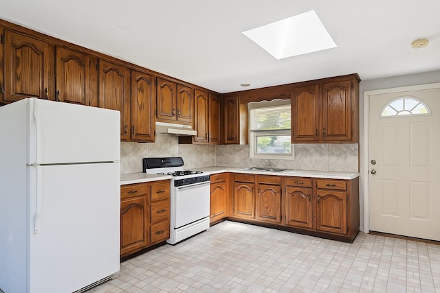 26 Beach Ave, Port Jefferson Station, NY 11776 - kitchen with white appliances, under cabinet range hood, a skylight, light countertops, and tasteful backsplash