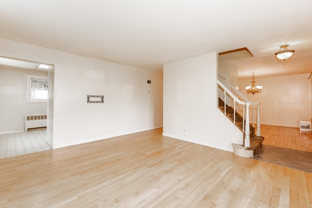 30 Jean Dr, North Babylon, NY 11703 - empty room featuring radiator, wood finished floors, stairway, a chandelier, and baseboards