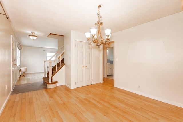 30 Jean Dr, North Babylon, NY 11703 - empty room featuring light wood-type flooring, stairway, a chandelier, and baseboards