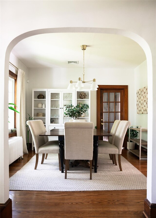 222 Lakeside Rd, Newburgh, NY 12550 - dining room featuring arched walkways, radiator heating unit, a chandelier, and wood finished floors