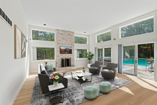 15 Elizabeth Ln, Quogue, NY 11959 - living area featuring light wood finished floors, a brick fireplace, a towering ceiling, and baseboards