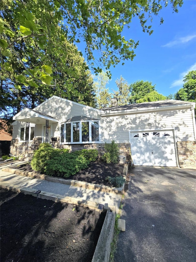 31 Whittier Blvd, Poughkeepsie, NY 12603 - view of front facade featuring a garage, driveway, a porch, a chimney, and stone siding