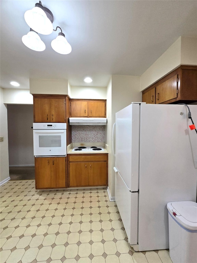 31 Whittier Blvd, Poughkeepsie, NY 12603 - kitchen featuring white appliances, under cabinet range hood, light floors, brown cabinetry, and light countertops