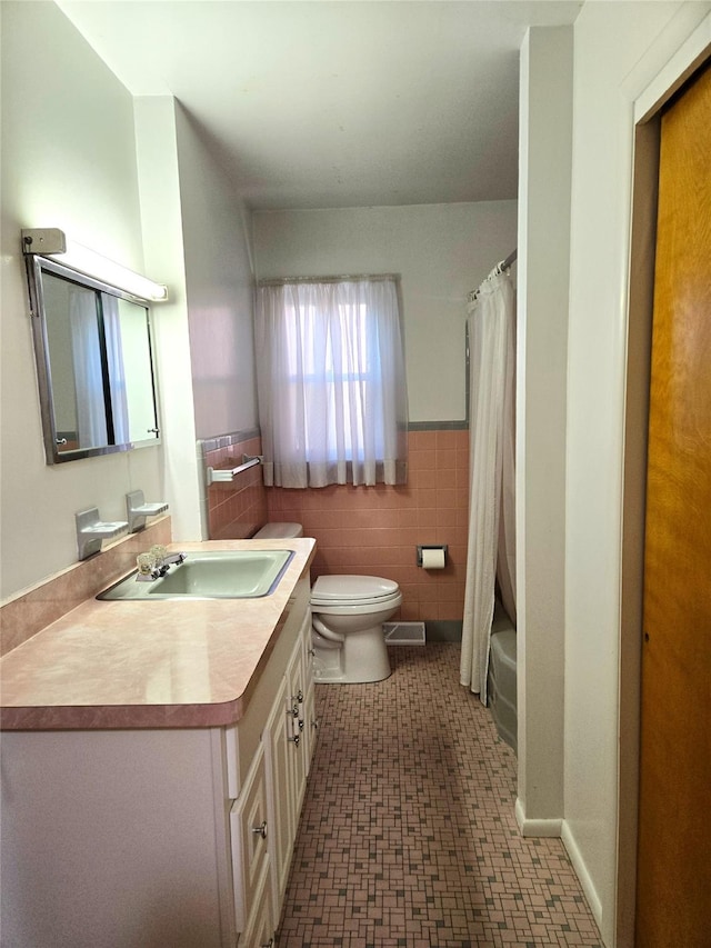 31 Whittier Blvd, Poughkeepsie, NY 12603 - bathroom featuring tile walls, toilet, vanity, and a wainscoted wall
